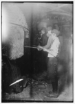 Lewis Hine child labor: Midnight in a Glass Works in Grafton, W. Va. Boys at the "Glory-Hole" where object is reheated before going to finisher. Location: Grafton, West Virginia.